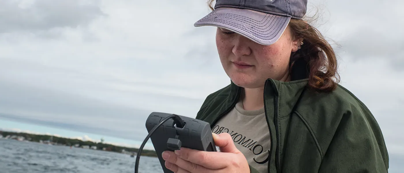 A U N E student uses a water temperature tool